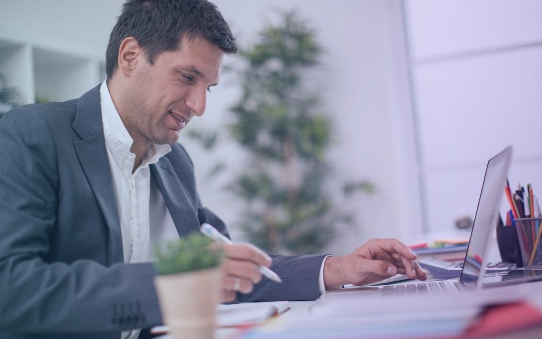 Photo d'un homme en tenue de travail souriant devant son ordinateur portable